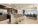 Modern kitchen featuring granite counters, dark wood cabinets, stainless steel appliances, and barstool seating at 3348 Lilac Way, Davenport, FL 33897