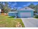 A beautiful home features a metal roof, blue exterior, attached one car garage, and manicured lawn at 713 Greenleaf Ln, Lake Wales, FL 33853