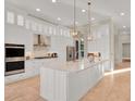 Modern kitchen featuring white cabinets, stainless steel appliances, a large island and pendant lighting at 7471 Gathering Loop, Reunion, FL 34747