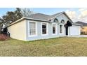 View of the side exterior, shows the light-colored siding and landscaped lawn of the home at 856 Jarnac Dr, Kissimmee, FL 34759