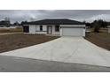 The front of this single-story home features a new concrete driveway, white exterior, and black trim at 113 Dogwood Drive Circle, Ocala, FL 34472