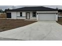 A modern, single-story home shows off it's fresh concrete driveway and minimalist white with black trim exterior at 113 Dogwood Drive Circle, Ocala, FL 34472