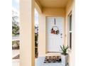 Inviting front porch with decorative wreath, potted plants, and a 'hello' welcome mat at 4823 Coral Castle Dr, Kissimmee, FL 34746