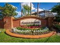 Entrance to Eagle Pointe features a brick sign, stone signage, flowers, and manicured plants at 563 Eagle Pointe S, Kissimmee, FL 34746