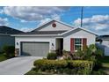 Inviting single-story home featuring a gray garage door, stone accents, and a lush, landscaped front yard at 1042 Heirloom Dr, Haines City, FL 33844