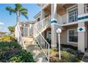 Close-up of condo stairs with white railing, leading to charming second-story units surrounded by greenery at 13829 Timberland Dr # 204, Orlando, FL 32824