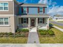 Charming two-story home featuring a welcoming front porch, manicured landscaping, and a blend of blue and neutral tones at 1860 Tohoqua Blvd, Kissimmee, FL 34744