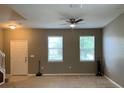 Neutral living room with ceiling fan, light-colored carpet, and large windows with horizontal blinds at 3742 Maidencain St, Clermont, FL 34714