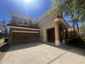 Two story tan home with a two car garage and a terracotta colored roof under a bright, sunny sky at 375 Orange Cosmos Blvd, Davenport, FL 33837