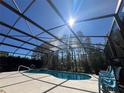 Screened-in pool with sunny skies and trees in the background offers a serene spot for relaxation and recreation at 375 Orange Cosmos Blvd, Davenport, FL 33837