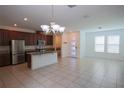 Open concept kitchen with stainless steel appliances, granite countertops and island with modern lighting at 7381 Alpine Butterfly Ln, Orlando, FL 32819