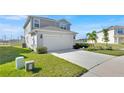 Two-story home with two-car garage, manicured lawn, and concrete driveway leading up to the house at 1562 Delightful Dr, Davenport, FL 33896