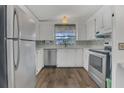 Bright kitchen featuring stainless steel appliances and white cabinetry, well lit by a window at 145 Kensington Park Dr, Davenport, FL 33897