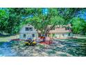 Charming home exterior featuring a large tree providing shade, a golf cart, and well-maintained landscaping at 15345 Rockridge Rd, Polk City, FL 33868