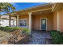 Inviting covered front porch with brick pavers, white columns, and manicured landscaping leading to a teal front door at 196 Knoll Wood Dr, Kissimmee, FL 34759