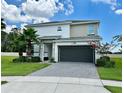 Two-story home boasts a brick paved driveway, dark garage door, manicured lawn, and well maintained landscaping at 2641 Calistoga Ave, Kissimmee, FL 34741