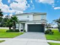 Two-story home boasts a brick paved driveway, dark garage door, manicured lawn, and well maintained landscaping at 2641 Calistoga Ave, Kissimmee, FL 34741