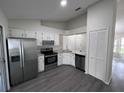 Modern kitchen with white cabinets, stainless steel appliances, and gray wood-look flooring at 3216 Fieldcrest Ter, Deltona, FL 32725