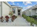 Front entrance with walkway, red flowering Hibiscus, and landscaped garden at 3930 Palazzo Pl, Winter Haven, FL 33884