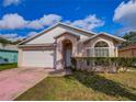 Well-kept single-story home featuring a two-car garage, arched entryway, and manicured landscaping at 4941 Luna Negra Dr, Orlando, FL 32811