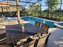 Relaxing screened-in patio with outdoor dining and lounge area overlooking sparkling swimming pool at 5411 Oakgrain Ct, Davenport, FL 33837