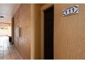 Neutral hallway featuring unit 111, with a decorative tile number above a dark brown door at 5578 Metrowest Blvd # 11, Orlando, FL 32811