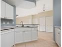 Bright kitchen featuring white cabinetry, stainless steel sink, and tiled flooring, with neutral walls at 5578 Metrowest Blvd # 11, Orlando, FL 32811