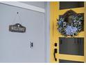 A cheerful yellow door with a decorative wreath and welcome sign adds charm to the home's entrance at 6699 Alder Rd, Harmony, FL 34773