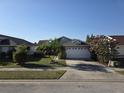 Well-kept single-story home featuring a two-car garage, landscaped lawn, and mature trees at 832 Whalebone Bay Dr, Kissimmee, FL 34741