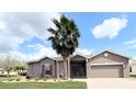 Inviting home with a mature palm tree in the front yard and a two-car garage at 901 Shorehaven Dr, Poinciana, FL 34759