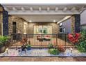 Inviting covered outdoor patio, featuring stone accents, a black metal railing, and colorful landscaping at 10196 Bucklow Hill Dr, Orlando, FL 32832