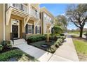 Exterior view of tan townhome with small balcony, landscaping and sidewalk at 1343 Flagstone Ave, Celebration, FL 34747