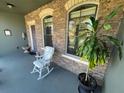 Inviting covered front porch with stone detailing, rocking chair and potted plants at 1820 Trophy Bass Way, Kissimmee, FL 34746