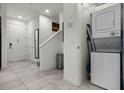 Bright entryway featuring tile flooring, a stacked washer/dryer, a staircase and direct access to the home at 2606 Roadster Ln, Kissimmee, FL 34746