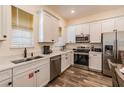 Modern kitchen featuring white cabinets, stainless steel appliances, and wood-look tile floors at 2958 Salted Rim Rd, Kissimmee, FL 34747