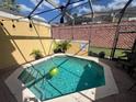 Relaxing screened-in pool area with a small pool, string lights, and a brick surround at 3136 Yellow Lantana Ln, Kissimmee, FL 34747