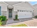 Home exterior with a two-car garage, stone accents, and a well-maintained front yard at 33436 Country House Dr, Sorrento, FL 32776