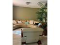 Living room with a beige sectional sofa, accent pillows, and a tall potted plant at 350 Corsica Ct, Kissimmee, FL 34758