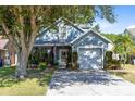 Inviting blue home with an attached garage and a beautiful, shaded front yard at 3741 Crossing Creek Blvd, St Cloud, FL 34772