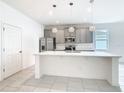 Bright kitchen featuring gray cabinets, pendant lighting, stainless appliances, and a large island at 417 Tisone Ln, Davenport, FL 33837