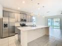 Bright kitchen featuring gray cabinets, pendant lighting, stainless appliances, and a large island at 417 Tisone Ln, Davenport, FL 33837