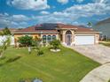 Attractive one-story home with lush green lawn and beautiful landscaping with solar panels on the roof at 5113 Sage Way, Kissimmee, FL 34758