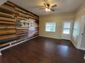 Bright living room featuring unique wood accent wall, ceiling fan, and dark wood floors at 713 Illinois Ave, St Cloud, FL 34769