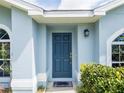 Close-up of the front door of a house, painted blue, with a small porch and manicured shrubbery at 790 Greenshank Dr, Haines City, FL 33844