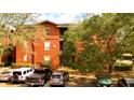 Eye-level exterior view of the red brick condo building with balcony and visible parking area at 107 Vista Verdi Cir # 129, Lake Mary, FL 32746