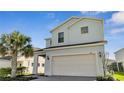 Two-story home with attached two-car garage, brick paver driveway, and mature palm tree in the front yard at 2471 Dubai St, Kissimmee, FL 34747