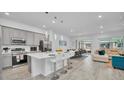 Open concept kitchen with white quartz countertops, stainless appliances, and bar seating leading to living area at 2536 Shanti Dr, Kissimmee, FL 34746