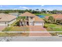 Inviting two-story home with a brick driveway, two-car garage, and a serene pond view in the background at 3723 Isles Arbor Ln, Kissimmee, FL 34746