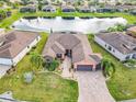 Aerial view of home with lake, lush landscaping and a paved driveway leading to a two-car garage at 484 Villa Park Rd, Kissimmee, FL 34759