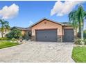 Exterior front view of home with a lush lawn, brick-paved driveway, two-car garage and stone-accented exterior at 484 Villa Park Rd, Kissimmee, FL 34759